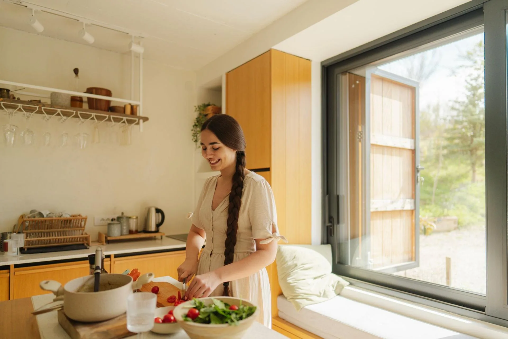 A woman preparing fresh vegetables in a bright, sunlit kitchen